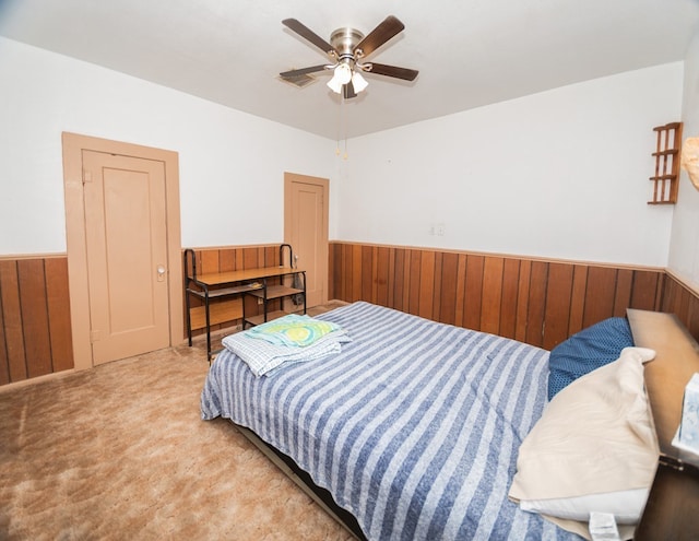 bedroom with ceiling fan, wood walls, and carpet floors