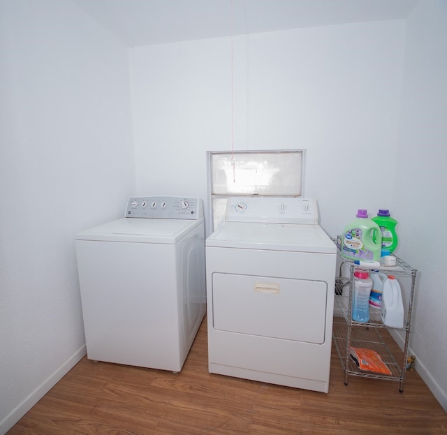 clothes washing area with hardwood / wood-style floors and washer and clothes dryer