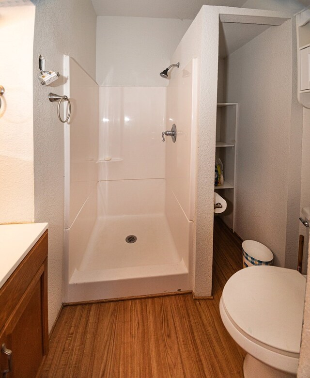 bathroom featuring hardwood / wood-style floors, toilet, walk in shower, and vanity