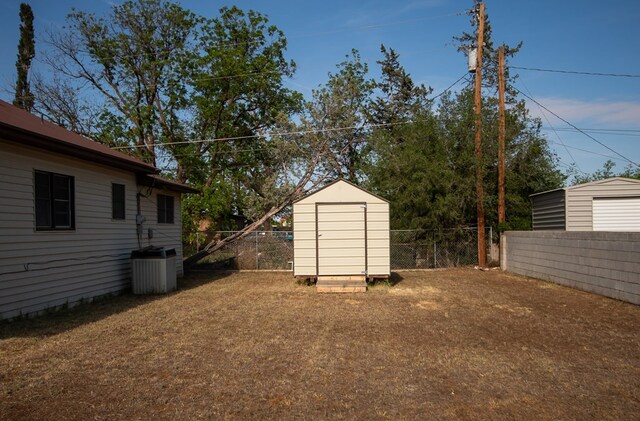 view of yard featuring a shed and central AC unit