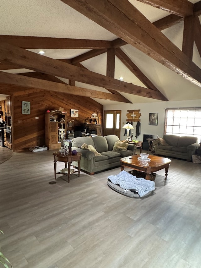 living room with wooden walls, vaulted ceiling with beams, and wood finished floors