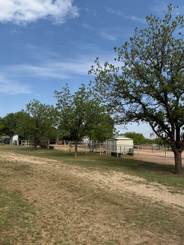 view of yard featuring fence, an outbuilding, and a rural view