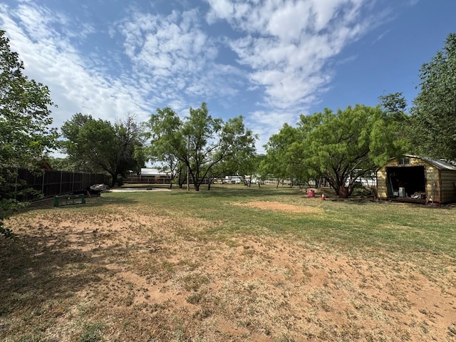 view of yard featuring fence, a storage unit, and an outbuilding