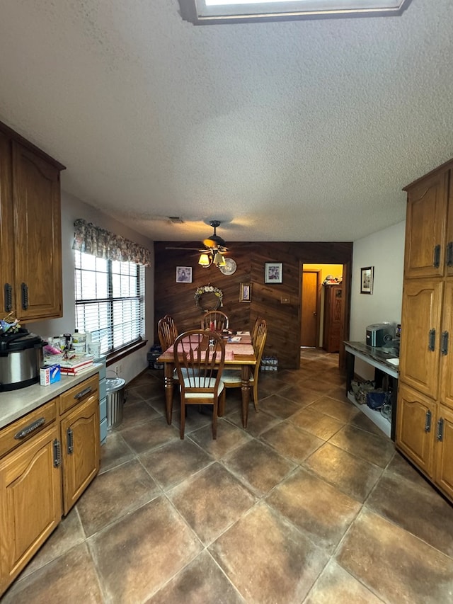 dining space featuring a ceiling fan, a textured ceiling, and wooden walls