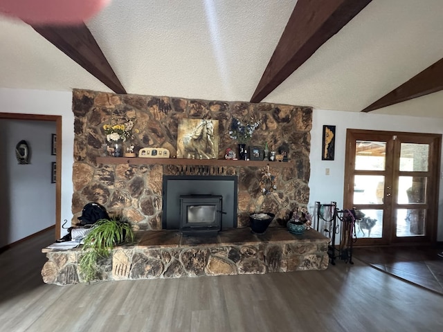 living room with a wood stove, a textured ceiling, french doors, wood finished floors, and beamed ceiling