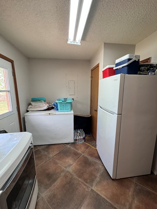 washroom with dark tile patterned floors, laundry area, and a textured ceiling