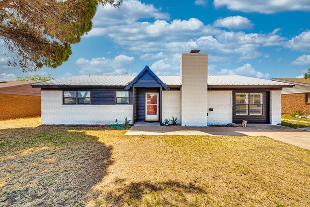 2724 E 11th St, Odessa, TX 79761 - ranch-style house with a front lawn, a chimney, brick siding, and metal roof
