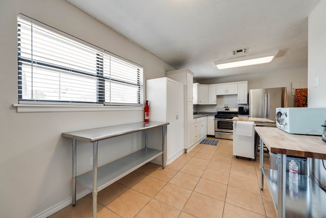 2724 E 11th St, Odessa, TX 79761 - kitchen featuring visible vents, stainless steel appliances, light tile patterned flooring, white cabinets, and wooden counters