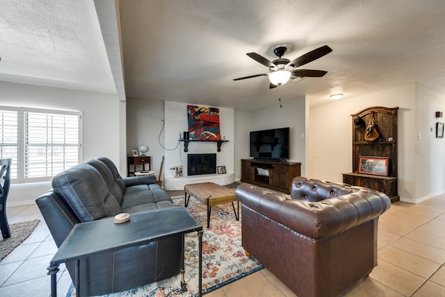 2724 E 11th St, Odessa, TX 79761 - living room with light tile patterned floors, baseboards, ceiling fan, a textured ceiling, and a large fireplace