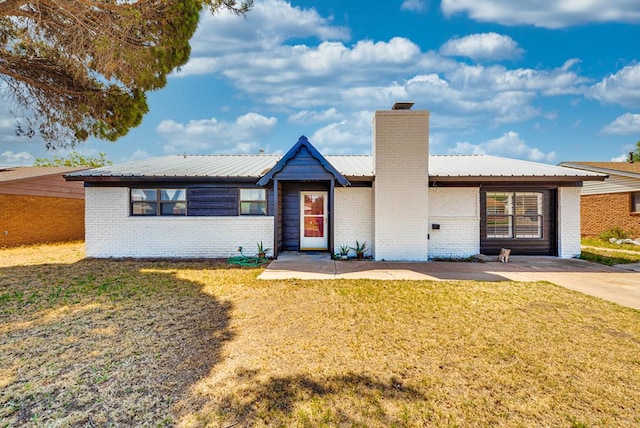 2724 E 11th St, Odessa, TX 79761 - ranch-style house featuring metal roof, brick siding, a chimney, and a front lawn