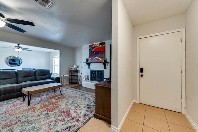 2724 E 11th St, Odessa, TX 79761 - living area featuring visible vents, a ceiling fan, a large fireplace, light tile patterned floors, and baseboards