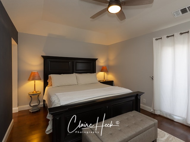 bedroom featuring a raised ceiling, wood finished floors, visible vents, and baseboards