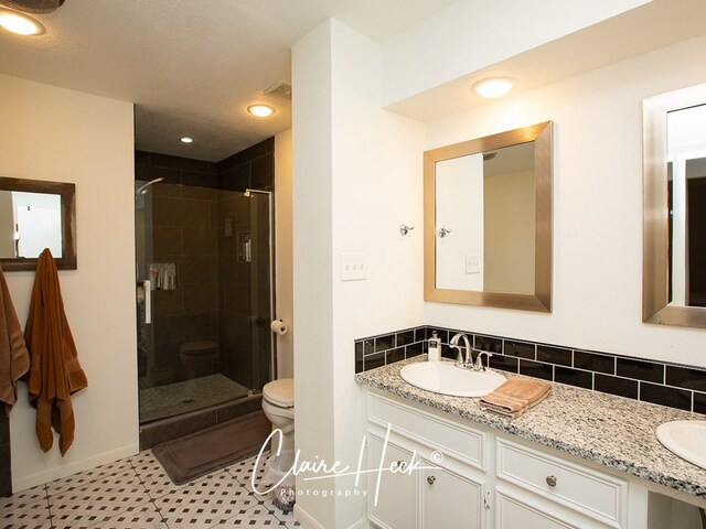 full bath featuring a stall shower, a sink, toilet, and double vanity