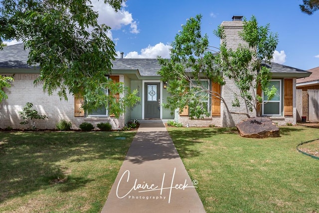 ranch-style home with a shingled roof, a chimney, and a front yard