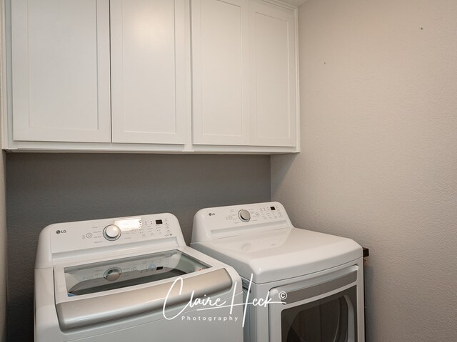 laundry room with cabinet space, washer and dryer, and a textured wall