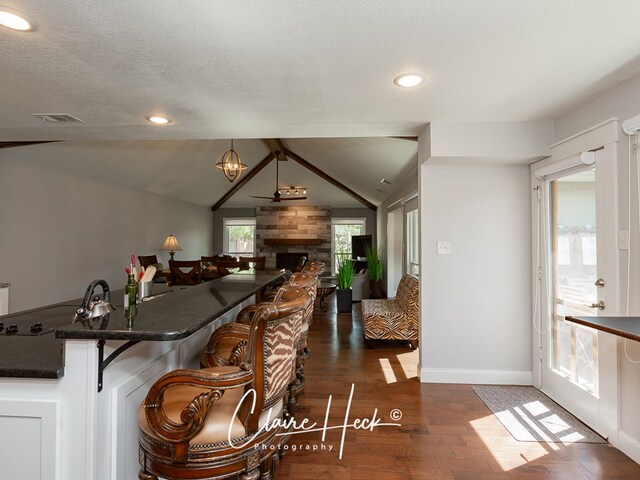 kitchen with dark countertops, open floor plan, visible vents, and lofted ceiling