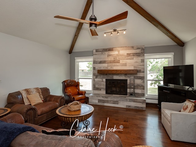 living room with plenty of natural light, a stone fireplace, lofted ceiling with beams, and wood finished floors