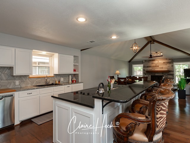 kitchen featuring dark wood-style flooring, open floor plan, a sink, dishwasher, and a kitchen breakfast bar