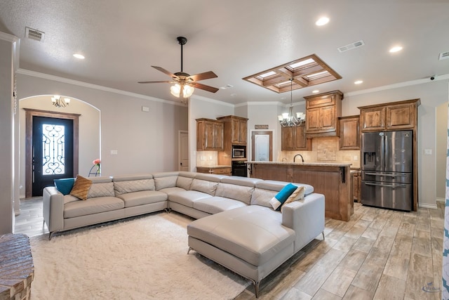 living room featuring ceiling fan with notable chandelier and crown molding