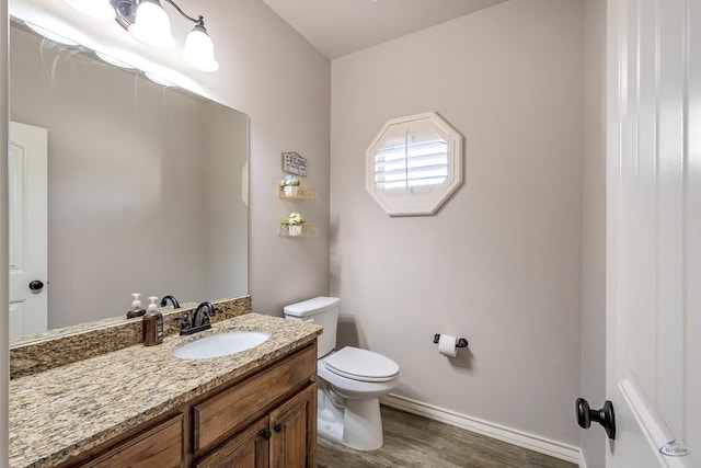 bathroom featuring toilet, vanity, and hardwood / wood-style flooring