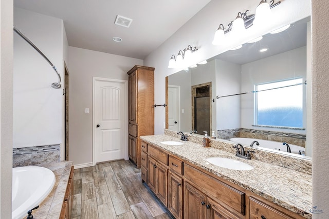 bathroom featuring wood-type flooring, vanity, and shower with separate bathtub