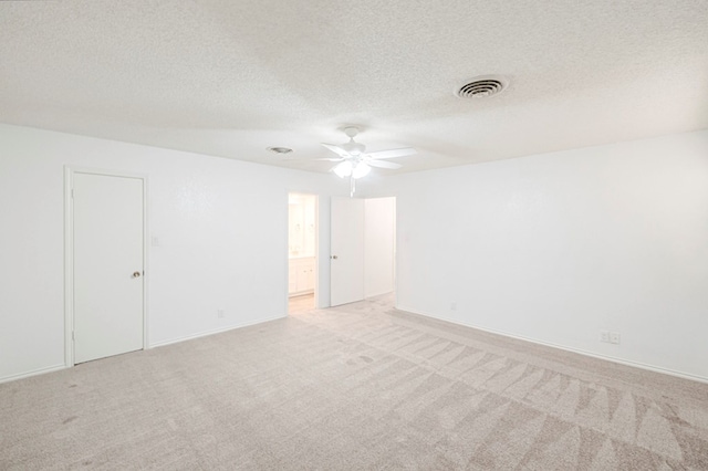 empty room featuring baseboards, visible vents, a ceiling fan, light colored carpet, and a textured ceiling