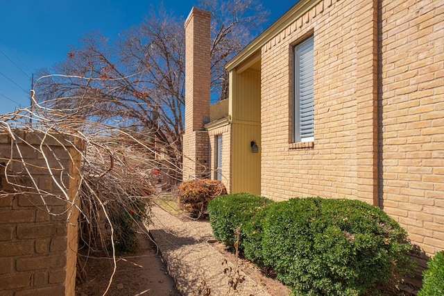 view of side of home featuring brick siding and a chimney