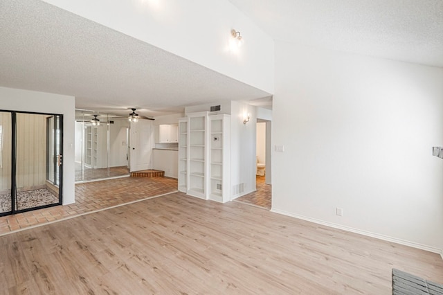 unfurnished living room with visible vents, ceiling fan, a textured ceiling, light wood-type flooring, and baseboards