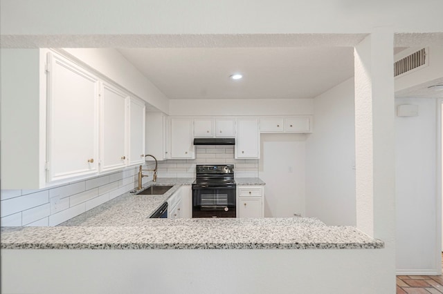 kitchen with light stone counters, under cabinet range hood, a sink, white cabinets, and black appliances