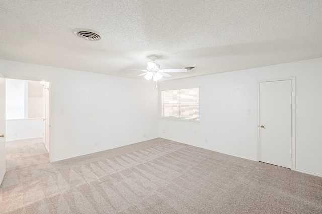 unfurnished room with light carpet, ceiling fan, a textured ceiling, and visible vents