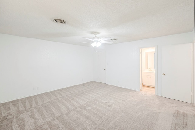 unfurnished room featuring a textured ceiling, ceiling fan, visible vents, and light colored carpet