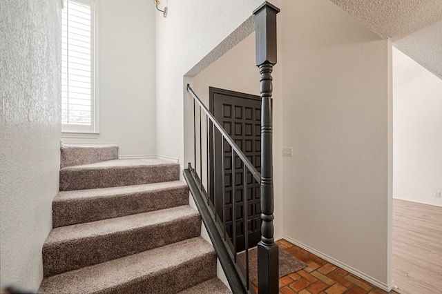 staircase featuring brick floor and baseboards