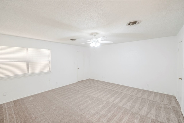 spare room with carpet floors, ceiling fan, visible vents, and a textured ceiling