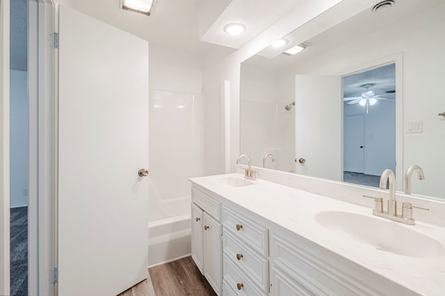 bathroom with double vanity, visible vents, a sink, and wood finished floors