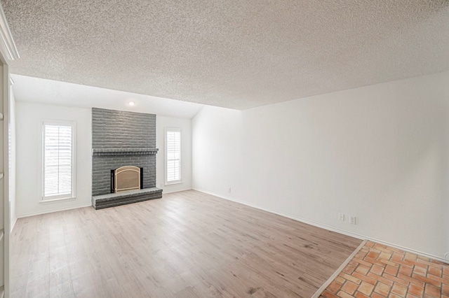 unfurnished living room featuring light wood-type flooring, a fireplace, baseboards, and a wealth of natural light