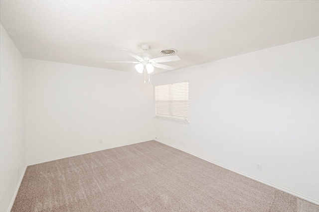 unfurnished room featuring visible vents, light colored carpet, ceiling fan, a textured ceiling, and baseboards