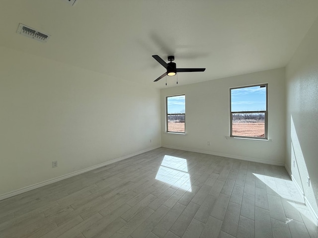 unfurnished room featuring baseboards, wood finished floors, visible vents, and a ceiling fan