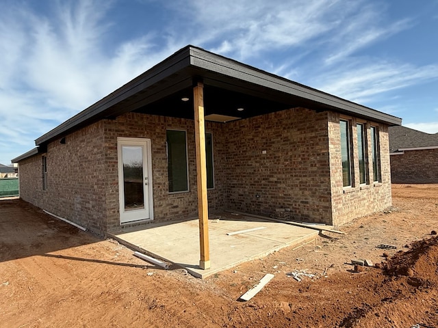 view of property exterior featuring a patio and brick siding