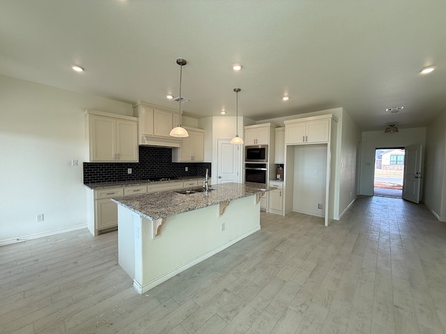 kitchen with light stone counters, stainless steel appliances, decorative backsplash, white cabinets, and a sink