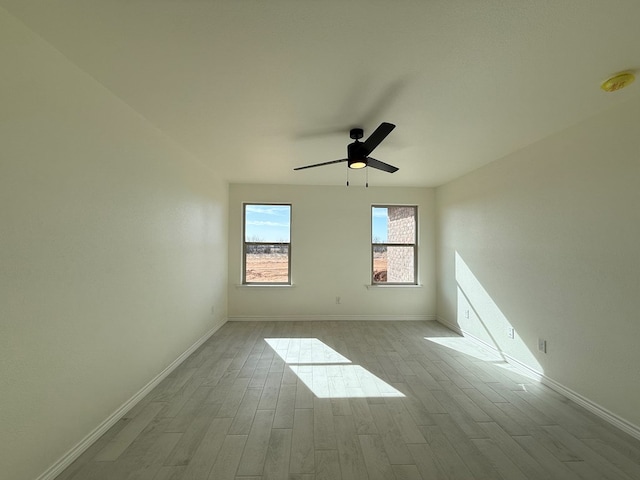 empty room featuring ceiling fan, baseboards, and wood finished floors