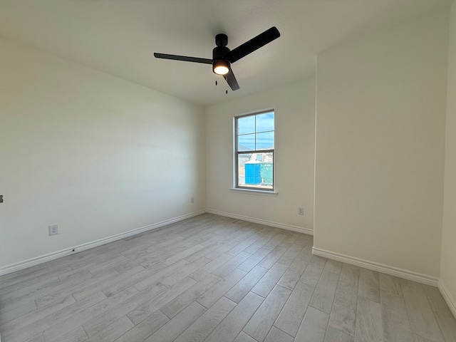 spare room featuring ceiling fan, light wood-style flooring, and baseboards