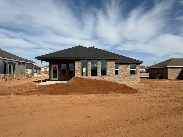 back of property featuring a shingled roof, a patio area, and brick siding