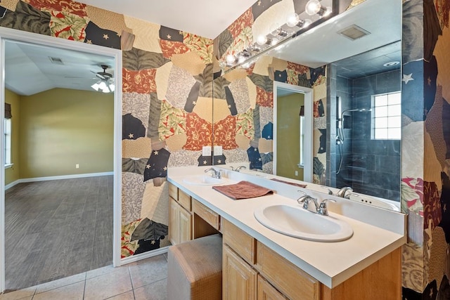 bathroom featuring tile patterned floors, a tile shower, vanity, vaulted ceiling, and ceiling fan