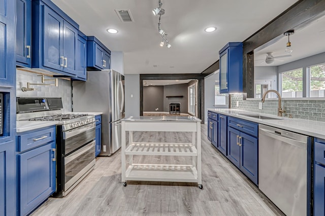 kitchen featuring appliances with stainless steel finishes, a sink, light countertops, blue cabinetry, and visible vents