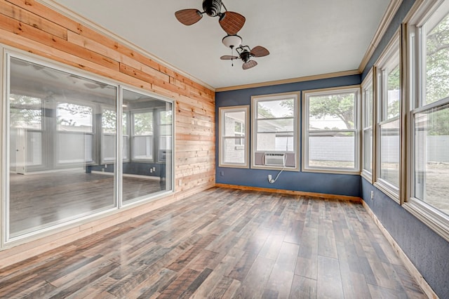 unfurnished sunroom featuring plenty of natural light, ornamental molding, wood walls, and wood finished floors