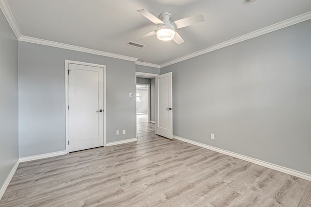 unfurnished bedroom featuring baseboards, ornamental molding, light wood-style flooring, and visible vents