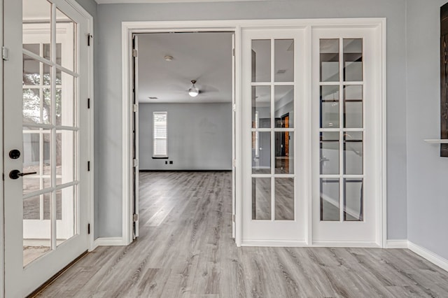 interior space with a ceiling fan, baseboards, french doors, and wood finished floors