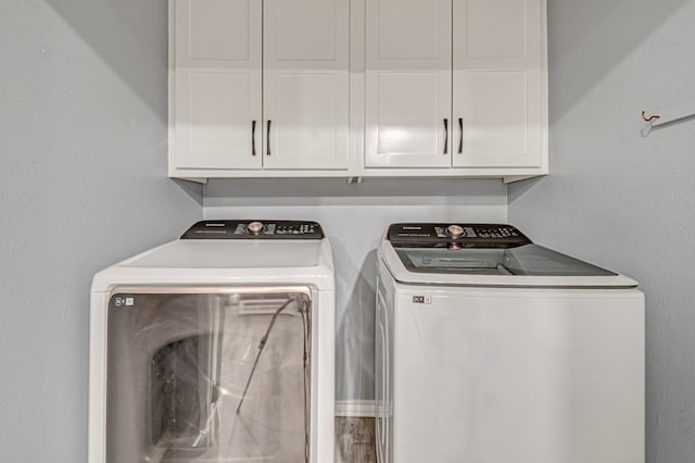 clothes washing area with washing machine and dryer and cabinet space