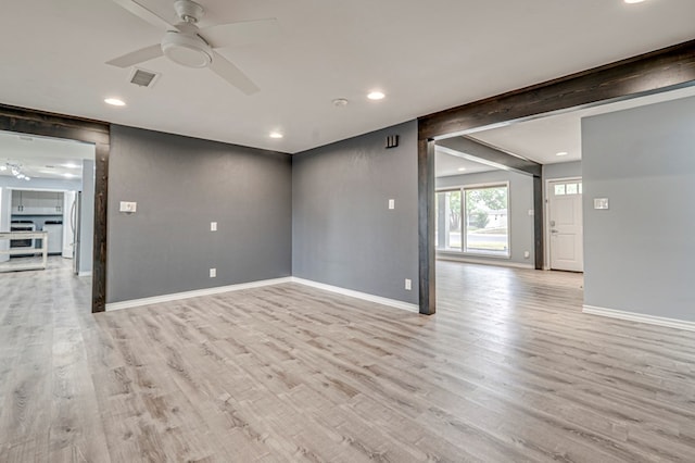 empty room featuring ceiling fan, visible vents, baseboards, and light wood-type flooring