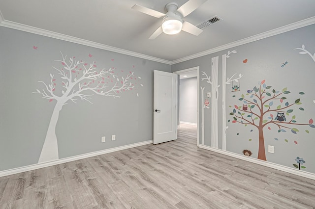 unfurnished room with visible vents, ornamental molding, wood finished floors, baseboards, and ceiling fan